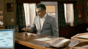 Eugene Levy ringing a bell at the front desk of a hotel