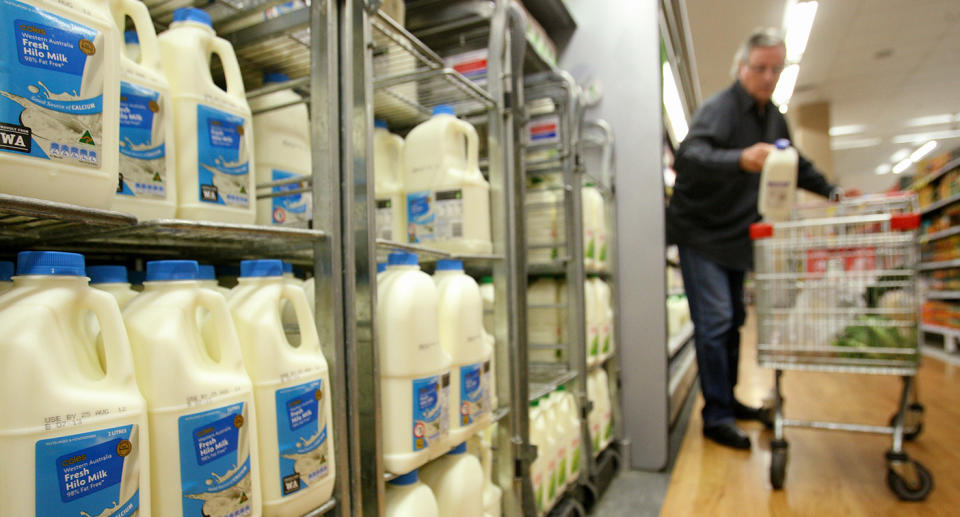 Coles shopper adding to trolley from milk fridge