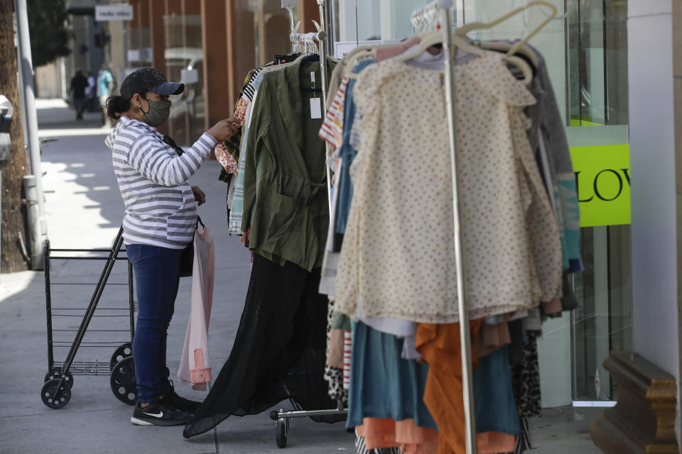 A woman shops for clothes Wednesday, May 27, 2020, in Los Angeles. California moved to further relax its coronavirus restrictions and help the battered economy. Retail stores, including those at shopping malls, can open at 50% capacity. (AP Photo/Marcio Jose Sanchez)