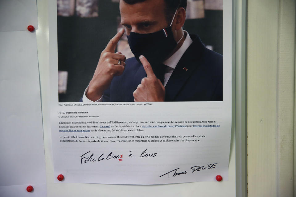 In this Friday, June 12, 2020 photo, a view of a poster of director Thomas Delise's message to employees showing a picture by Ian Langsdon of Emmanuel Macron wearing a mask, on the office door in Chanteclair Hosiery, a French knitwear clothing manufacturer, in Saint Pouange, east of Paris. The French praised the altruism of luxury goods companies such as LVMH, Kering and Chanel for diverting their production facilities to make millions of face masks for the public during the peak of their country's coronavirus outbreak. Now, the companies that helped France avoid a dangerous shortage say they need help unloading a surplus of 20 million washable masks. (AP Photo/Francois Mori)