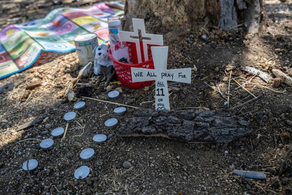 Eleven candles, flowers, and crosses lie on Thursday near the tree where three people died and eight were injured along San Juan Road the night before.