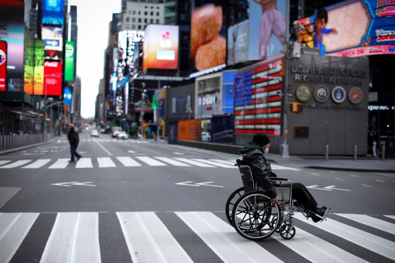 Man in wheelchair crosses nearly empty 7th Avenue in Times Square in Manhattan during the outbreak of the coronavirus disease (COVID-19) in New York