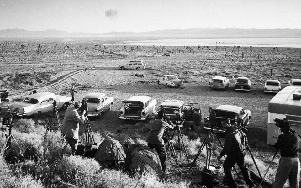 Reporters watch an explosion in 1958 - Getty