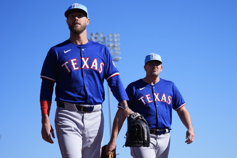 Texas Rangers pitchers Shane Greene, left, and Jonathan Holder, right, walk to the bullpen during spring training baseball workouts, Wednesday, Feb. 14, 2024, in Surprise, Ariz. (AP Photo/Lindsey Wasson)