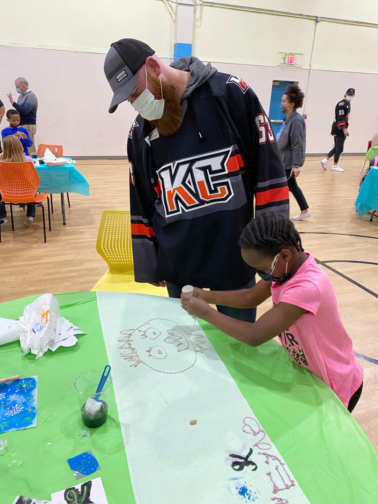 Kansas City's Sean Weller watches 9-year-old Kennyeyae Butler put the finishing touches on a portrait of the Mavericks forward as the ECHL team visited the Independence Boys & Girls Club Wednesday to decorate table runners that will be used at the upcoming Dinner on Ice event at Cable Dahmer Arena. The charity event did not take place last season because of COVID-19 restrictions and is one of the biggest money-raising events for the local Boys & Girls Clubs.