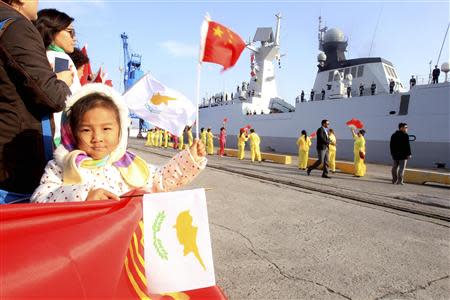 A child waves national flags of China (top) and Cyprus as the Chinese frigate Yancheng (R) comes in to dock at Limassol port, January 4, 2014. REUTERS/Andreas Manolis