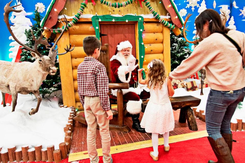 Leo Sabatino, 9, and his five-year-old sister, Elle, give Santa high fives during a visit in Santa’s Wonderland at Bass Pro Shop in Cary on Thursday evening, Nov. 11, 2021. Duane Reaugh has professionally worked as Santa for seven years.