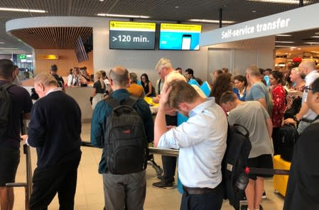 People and staff wait at Amsterdam Schiphol airport