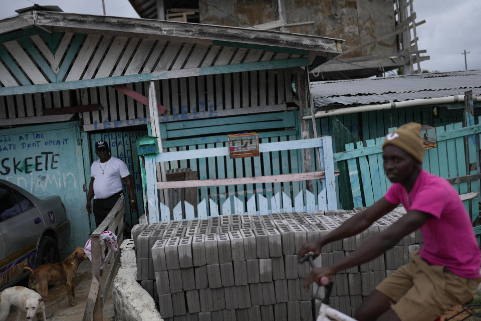 Steve Skete, back left, stands next to one of his singing birds in front of his house in Georgetown, Guyana, Saturday, April 22, 2023. Skete's birds have won several competitions, earning himself a name in the songbirds races, that are a Guyanese centuries-old tradition. (AP Photo/Matias Delacroix)