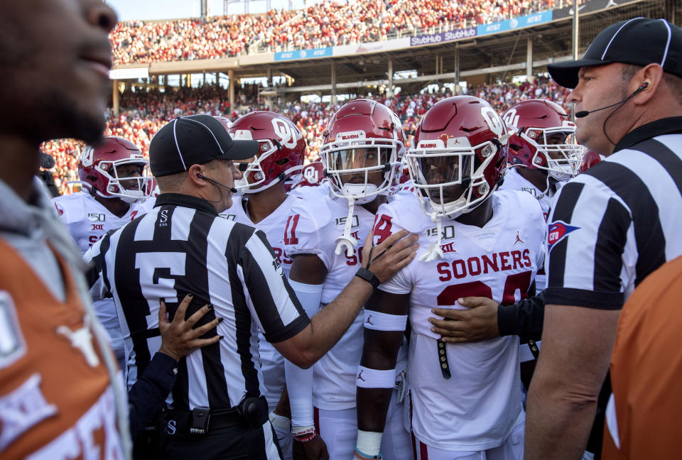Referees keep Oklahoma players from interacting with Texas players as they leave the field after pregame warmups before an NCAA college football game at the Cotton Bowl, Saturday, Oct. 12, 2019, in Dallas. Oklahoma won 34-27. (AP Photo/Jeffrey McWhorter)