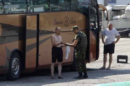 A Ukrainian serviceman checks the hands of a bus passenger at a checkpoint near the eastern Ukrainian town of Debaltseve, August 16, 2014. REUTERS/Valentyn Ogirenko
