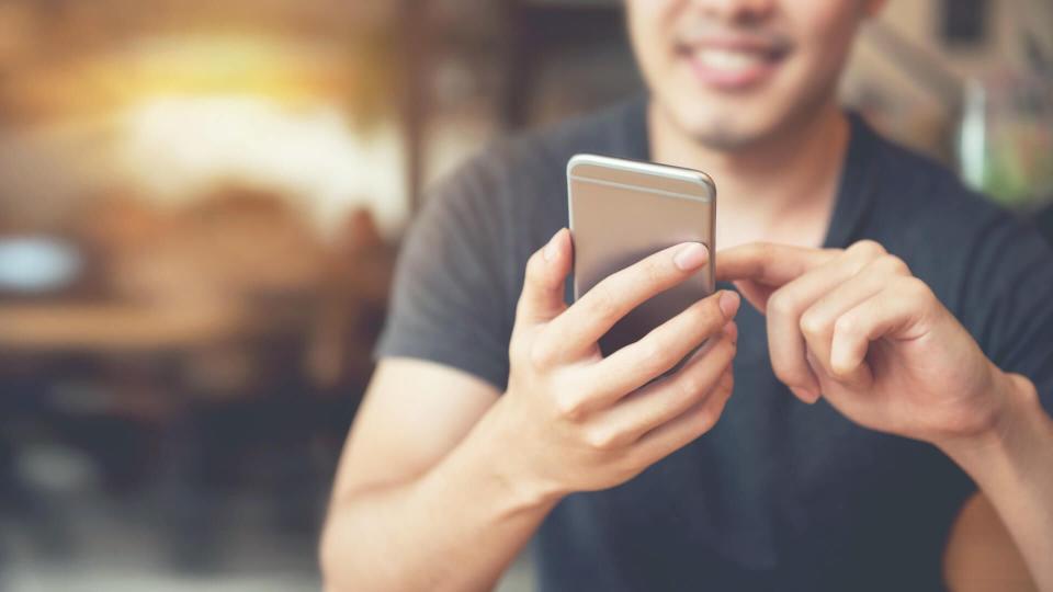 Happy man using smartphone at modern coffee shop, he chatting Online Messaging on mobile phone.