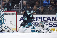 Seattle Kraken defenseman Jamie Oleksiak (24) reaches for the puck in an attempt to score with San Jose Sharks goaltender Devin Cooley, bottom right, looking back during the second period of an NHL hockey game, Thursday, April 11, 2024, in Seattle. (AP Photo/John Froschauer)