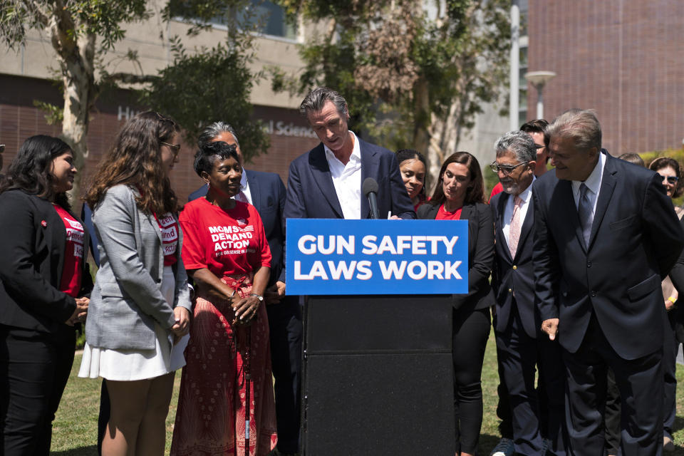 State officials and gun violence survivors watch as California Gov. Gavin Newsom signs a gun control law during a news conference held on the campus of Santa Monica College in Santa Monica, Calif., Friday, July 22, 2022. Newsom signed the law Friday, a month after conservative justices overturned women's constitutional right to abortions and undermined gun control laws in states including California. (AP Photo/Jae C. Hong)