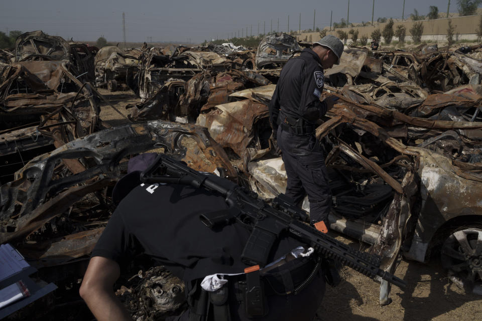 Israeli police officers inspect charred vehicles burned in the bloody Oct. 7 cross-border attack by Hamas militants, outside the town of Netivot, southern Israel, Sunday, Nov. 5, 2023. The vehicles were collected and placed in an area near the Gaza border after the attack, in which 1,400 people were killed and some 240 people were taken hostage. (AP Photo/Leo Correa)