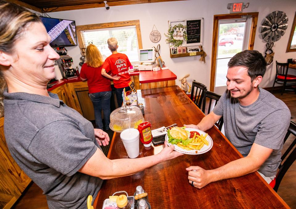 Alicia Quest, restaurant manager, delivers Josh Klemons his lunch on Wednesday at Papy's Place. Scott Homan and his wife, Wanda, purchased the old Saddle Rack Cafe in Anthony, renovated the building and renamed it Papy's Place. Scott said he was driving by the restaurant shortly after purchasing the building and the grandchildren yelled out "Look, there's Papy's Place." The name stuck.