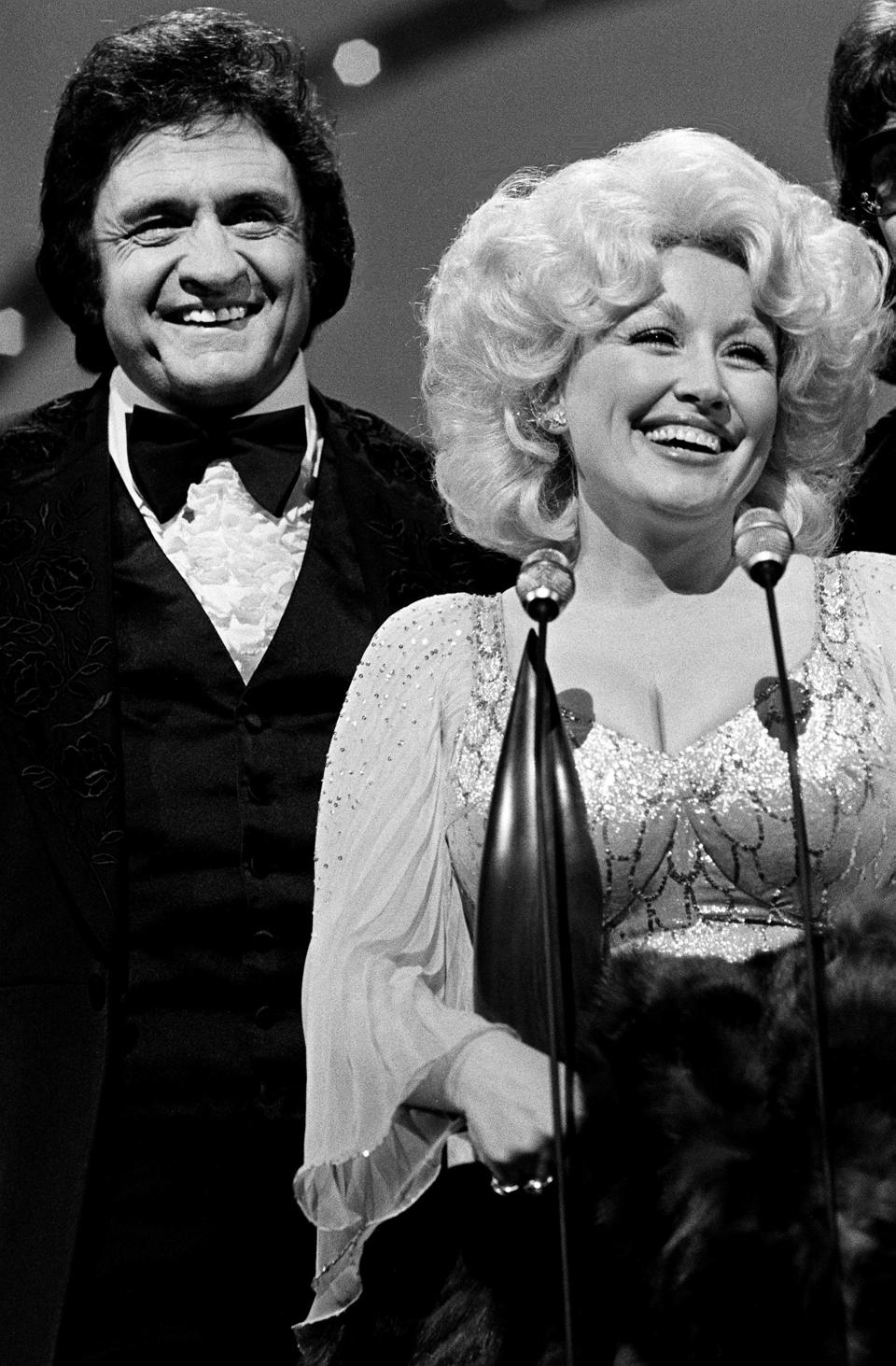Dolly Parton speaks after winning the Entertainer of the Year award during the 12th annual CMA Awards show at the Grand Ole Opry House on Oct. 9, 1978. Looking on is presenter and host Johnny Cash.