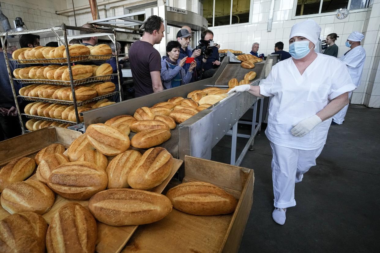 FILE - A group of foreign journalists observe the baking of bread according to the recipes of the Soviet era in Skadovsk, Kherson region, south Ukraine, on May 20, 2022. According to Russian state TV, the future of the Ukrainian regions occupied by Moscow's forces is all but decided: Referendums on becoming part of Russia will soon take place there, and the joyful residents who were abandoned by Kyiv will be able to prosper in peace. In reality, the Kremlin appears to be in no rush to seal the deal on Ukraine's southern regions of Kherson and Zaporizhzhia and the eastern provinces of Donetsk and Luhansk. (AP Photo)