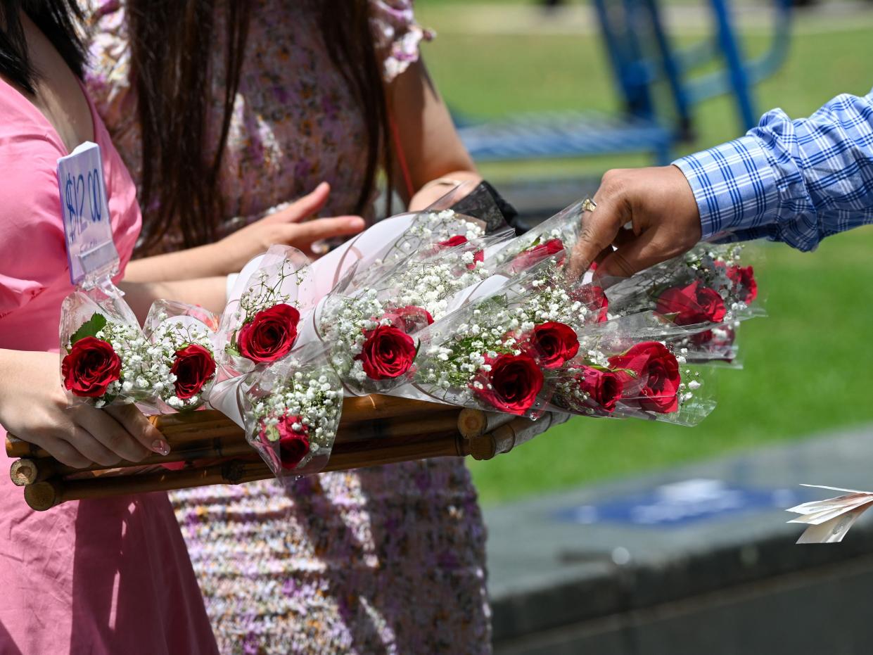 A man wearing a checked shirt takes a stalk of roses from a basket at the Raffles Place financial business district.