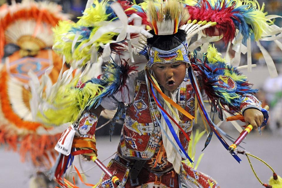 Boy dressed in colorful ceremonial garb dances.
