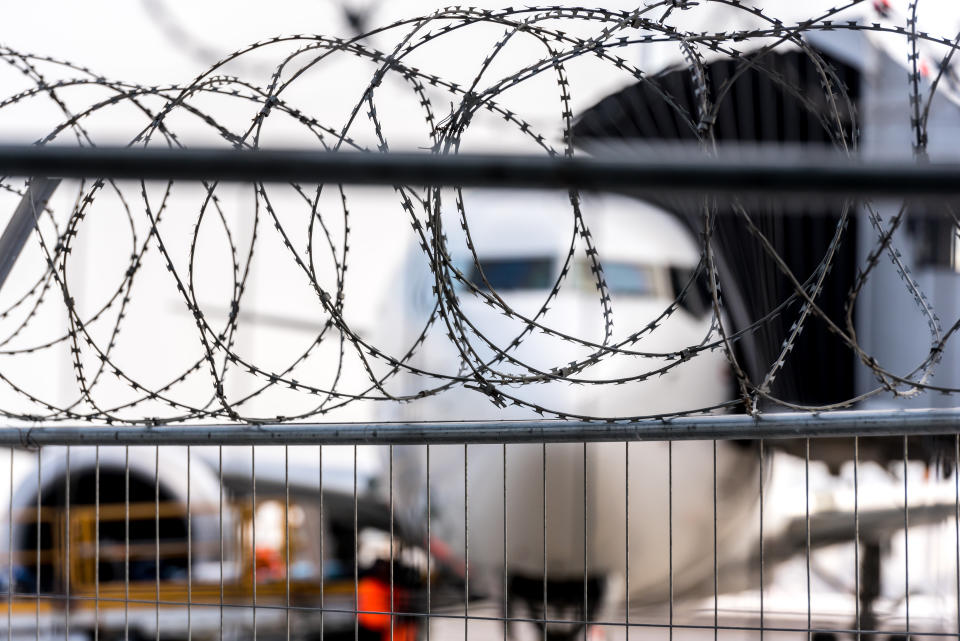 Airport security zone. Blurred aircraft behind a barbed wire fence. Illustration of the incident in aviation transport.