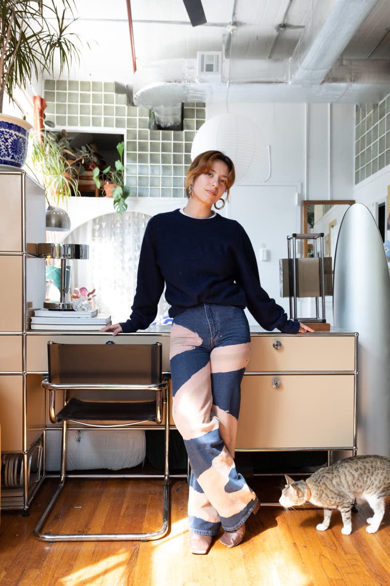 Dweller standing in front of desk in eclectic apartment.