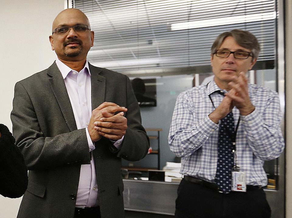 Two men applauding in newsroom.