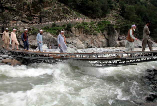 People cross a river on a bridge damaged by floodwaters, in the town of Bahrain, Pakistan on Aug. 30, 2022. The United Nations and Pakistan issued an appeal Tuesday for $160 million in emergency funding to help millions affected by record-breaking floods that have killed more than 1,150 people since mid-June. (Photo: Naveed Ali/AP)