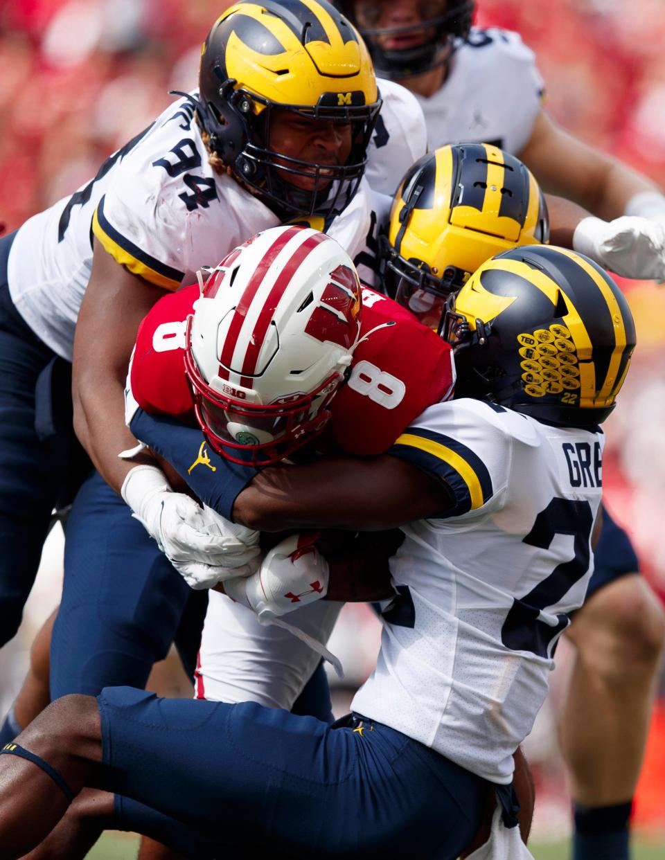 Wisconsin Badgers running back Jalen Berger is tackled by Michigan Wolverines defensive back Gemon Green (22) and defensive end Kris Jenkins (94) during the third quarter Oct. 2, 2021 at Camp Randall Stadium in Madison, Wis.