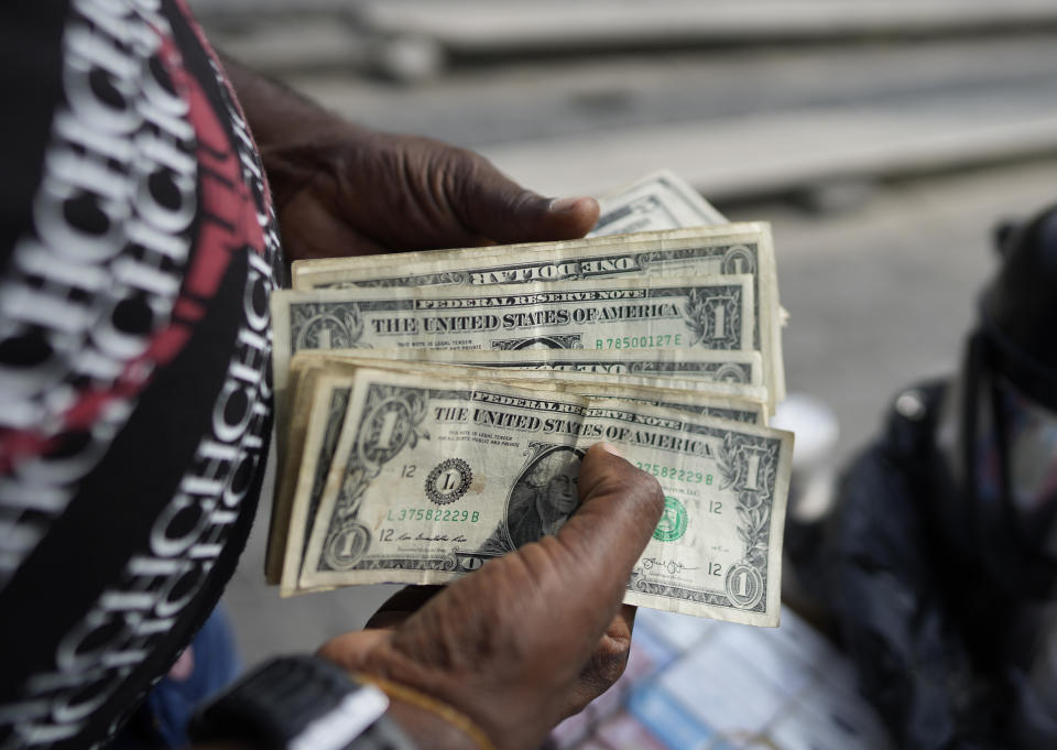 A street vendor, who sells coffee and cigarettes, counts her dollars in Caracas, Venezuela, Friday, Oct. 1, 2021. A new currency with six fewer zeros debuts Friday in Venezuela, whose currency has been made nearly worthless by years of the world's worst inflation. The new currency tops out at 100 bolivars, a little less than $25 until inflation starts to eat away at that as well. (AP Photo/Ariana Cubillos)