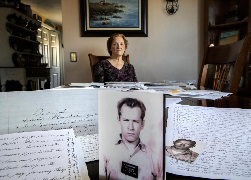 Janet Uhlar sits for a photo at her dining room table with an arrangement of letters and pictures she received through her correspondence with imprisoned Boston organized crime boss James "Whitey" Bulger, Friday, Jan. 31, 2020, in Eastham, Mass. Uhlar was one of 12 jurors who found Bulger guilty in a massive racketeering case, including involvement in 11 murders. But now she says she regrets voting to convict Bulger on the murder charges, because she learned he was an unwitting participant in a secret CIA experiment in which he was dosed with LSD on a regular basis for 15 months. (AP Photo/David Goldman)