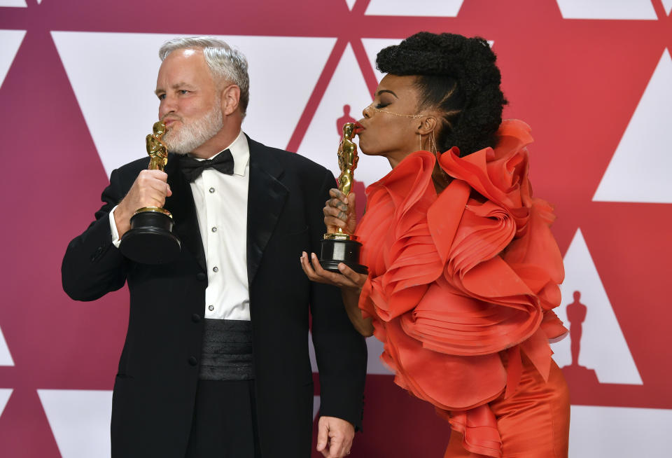 Jay Hart, left, and Hannah Beachler kiss their awards for best production design for "Black Panther" in the press room at the Oscars on Sunday, Feb. 24, 2019, at the Dolby Theatre in Los Angeles. (Photo by Jordan Strauss/Invision/AP)