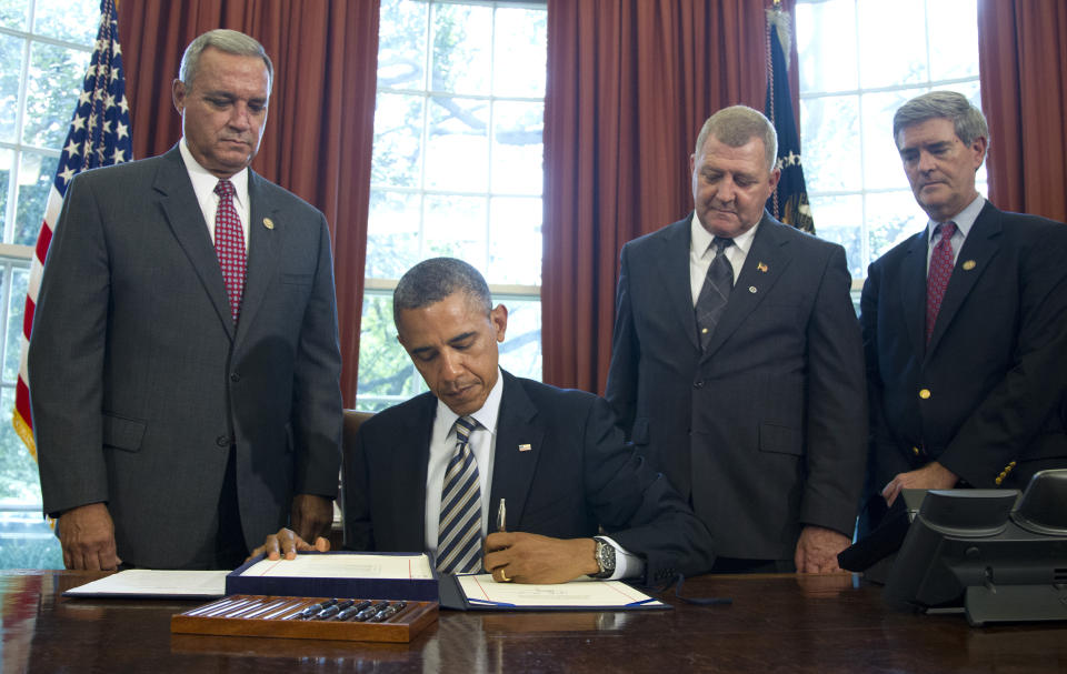 President Barack Obama signs the Honoring America's Veterans and Caring for Camp Lejeune Families Act of 2012, Monday, Aug. 6, 2012, in the Oval Office at the White House in Washington. From left are, Rep. Jeff Miller, R-Fla., Jerry Ensminger, former Master Sergeant, USMC, who served at Camp Lejeune and advocated on behalf of affected veterans and families, and Rep. Brad Miller, D-Fla.. (AP Photo/Haraz N. Ghanbari)