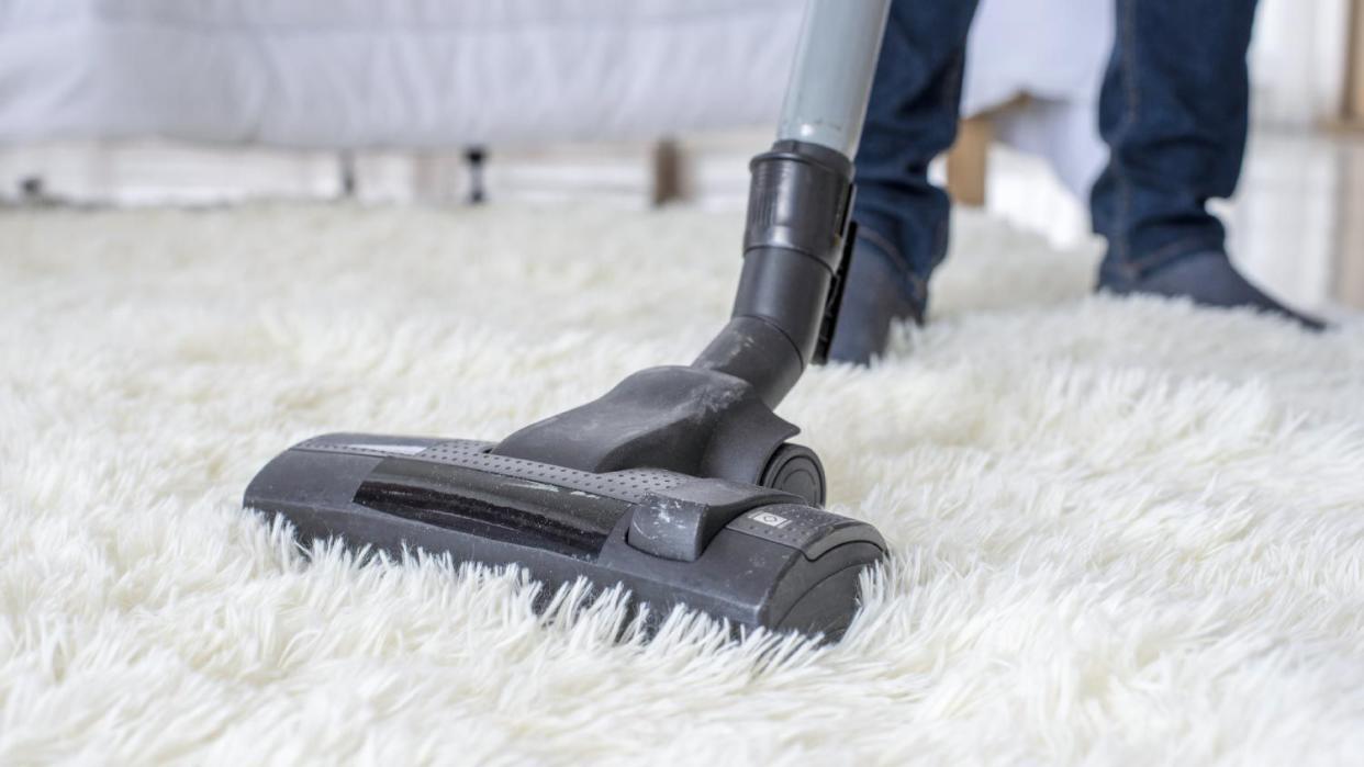 A man vacuuming on a carpet