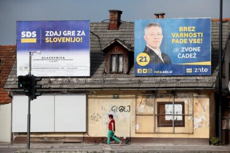 A woman walks under election posters of the Social democratic party (SDS) for general elections in Ljubljana, Slovenia, May 31, 2018. REUTERS/Borut Zivulovic