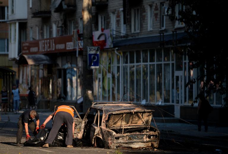 Officials remove a corpse from a burned car in downtown Donetsk, eastern Ukraine on August 27, 2014