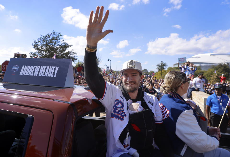 Texas Rangers pitcher Andrew Heaney waves to fans with his newborn in a carrier during a parade for the baseball World Series-champion Rangers near Globe Life Field in Arlington, Texas, Friday, Nov. 3, 2023. (Tom Fox/The Dallas Morning News via AP, Pool)