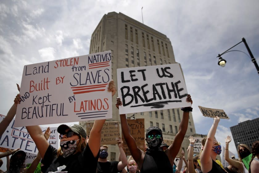 People hold signs during a rally in downtown Kansas City, Mo., Friday, June 5, 2020, to protest the death of George Floyd who died after being restrained by Minneapolis police officers on May 25. (AP Photo/Charlie Riedel)