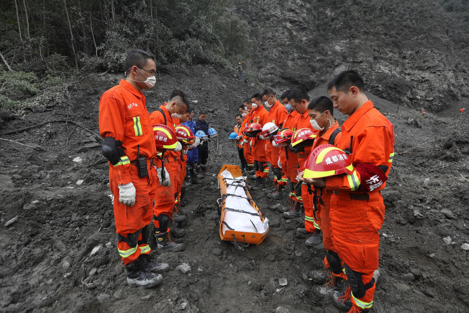 Rescue workers stand in silent tribute before evacuating a body