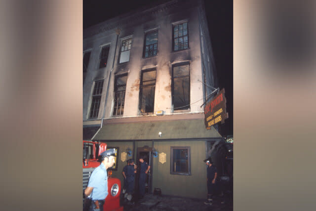 Firemen and rescue workers look up at the burned out bar and hotel