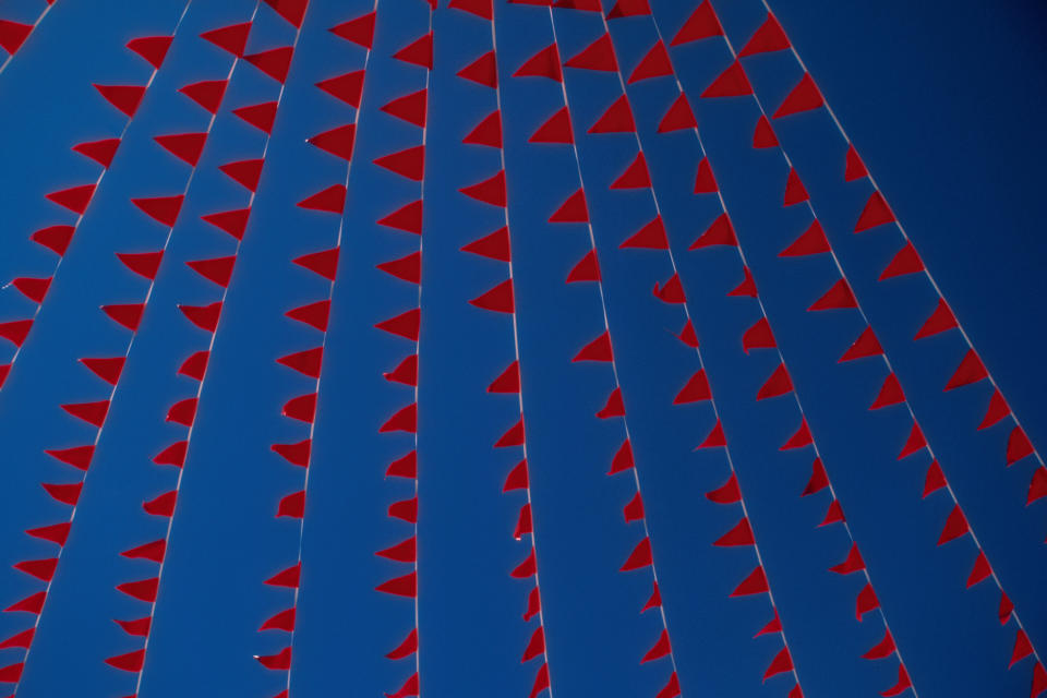 Image of red flags against a blue sky.