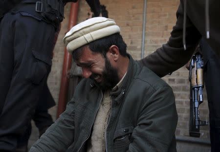 A man is comforted as he mourns the death of a relative after a suicide attack at a government office, in Mardan, Pakistan, December 29, 2015. REUTERS/Fayaz Aziz