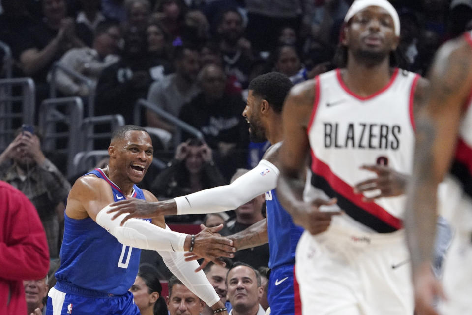 Los Angeles Clippers guard Russell Westbrook, left, celebrates with forward Paul George, center, after scoring as Portland Trail Blazers forward Jerami Grant walks away during the first half of an NBA basketball game Wednesday, Oct. 25, 2023, in Los Angeles. (AP Photo/Mark J. Terrill)