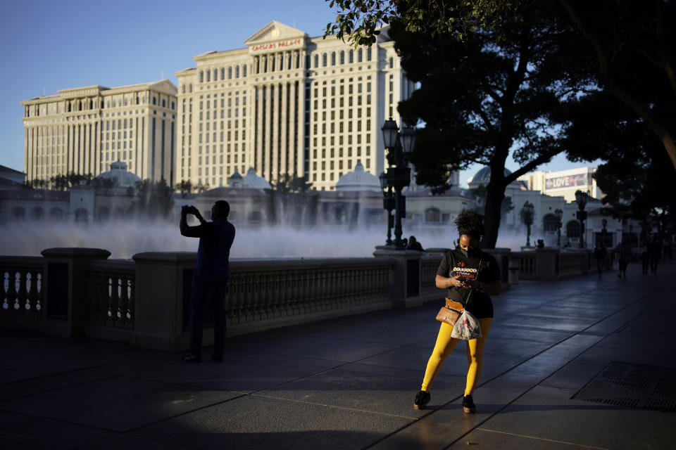 People walk along the Las Vegas Strip, Thursday, Nov. 19, 2020, in Las Vegas. As the coronavirus surges to record levels in Nevada, the governor has implored residents to stay home. But Democrat Steve Sisolak has also encouraged out-of-state visitors, the lifeblood of Nevada's limping economy, to come to his state and spend money in Las Vegas. (AP Photo/John Locher)