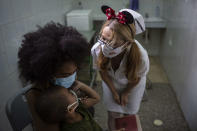 A nurse consoles a child after he was injected with a dose with a dose of the Soberana-02 COVID-19 vaccine, at a clinic in Havana, Cuba, Thursday, Sept. 16, 2021. Cuba began inoculating children as young as 2-years-old with locally developed vaccines on Thursday. (AP Photo/Ramon Espinosa)