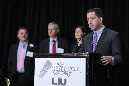Glenn Greenwald (L) speaks to the audience as his colleagues (L-R) Barton Gellman, Ewen MacAskill and Laura Poitras listen to him while they receive the George Polk Awards in New York, April 11, 2014. REUTERS/Eduardo Munoz