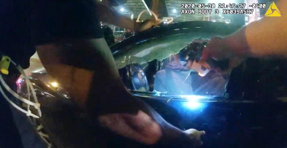 In this Saturday, May 30, 2020, photo taken from police body camera video released by the Atlanta Police Department, an officer points his handgun at Messiah Young while the college student is seated in his vehicle, in Atlanta. The following day, Atlanta's mayor two police officers were fired and three others placed on desk duty over excessive use of force during the arrest of Young and fellow college student Taniyah Pilgrim, seated in the passenger side of the car. (Atlanta Police Department via AP)