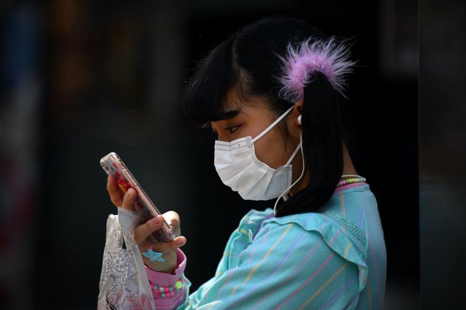 <span class="caption">Getting kids to put down their phones doesn't have to be a battle.</span> <span class="attribution"><a class="link " href="https://www.gettyimages.com/detail/news-photo/girl-wearing-a-face-mask-checks-her-phone-as-she-waits-in-news-photo/1206683259" rel="nofollow noopener" target="_blank" data-ylk="slk:Carl Court/Getty Images;elm:context_link;itc:0;sec:content-canvas">Carl Court/Getty Images</a></span>