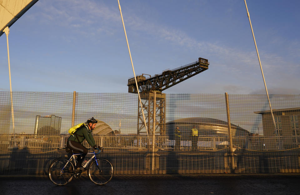 A person cycles near the venue of the COP26 U.N. Climate Summit in Glasgow, Scotland, Thursday, Nov. 4, 2021. The U.N. climate summit in Glasgow gathers leaders from around the world, in Scotland's biggest city, to lay out their vision for addressing the common challenge of global warming. (AP Photo/Alberto Pezzali)