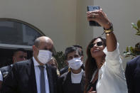 A Lebanese woman takes a selfie with French Foreign Minister Jean-Yves Le Drian, during his visit to the Carmel Saint Joseph school in Mechref district, south of the capital Beirut, Lebanon, Friday, July 24, 2020. Le Drian pledged on Friday €15 million ($17 million) in aid to Lebanon's schools, struggling under the weight of the country's major economic crisis. (AP Photo/Bilal Hussein)